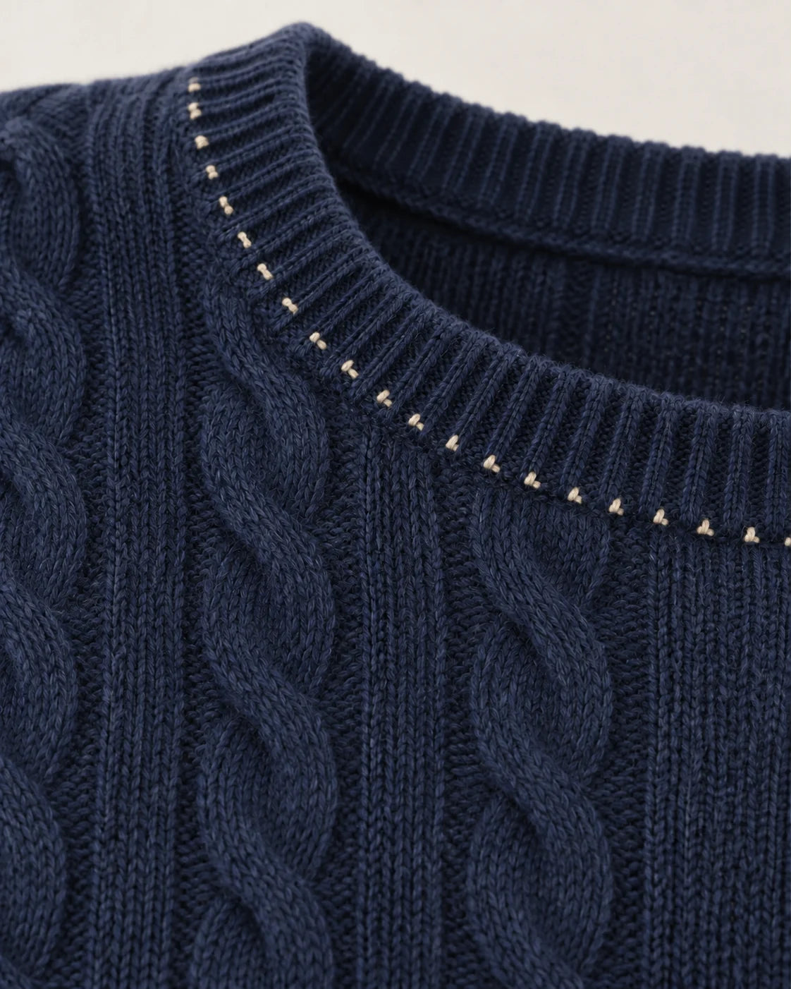A fine hand-stitched line around a cable-knit neckline