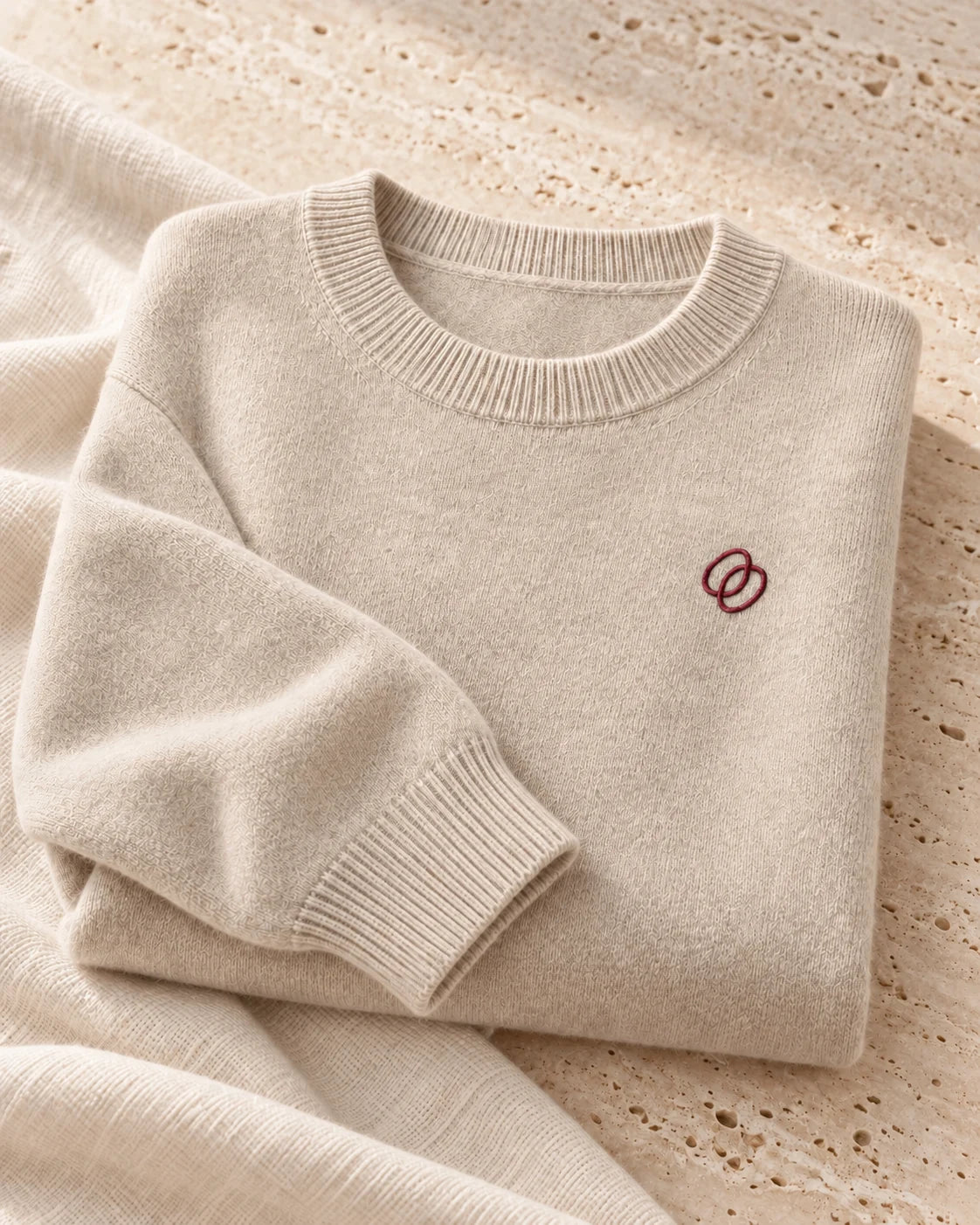 An ivory cashmere crew with a burgundy embroidered emblem